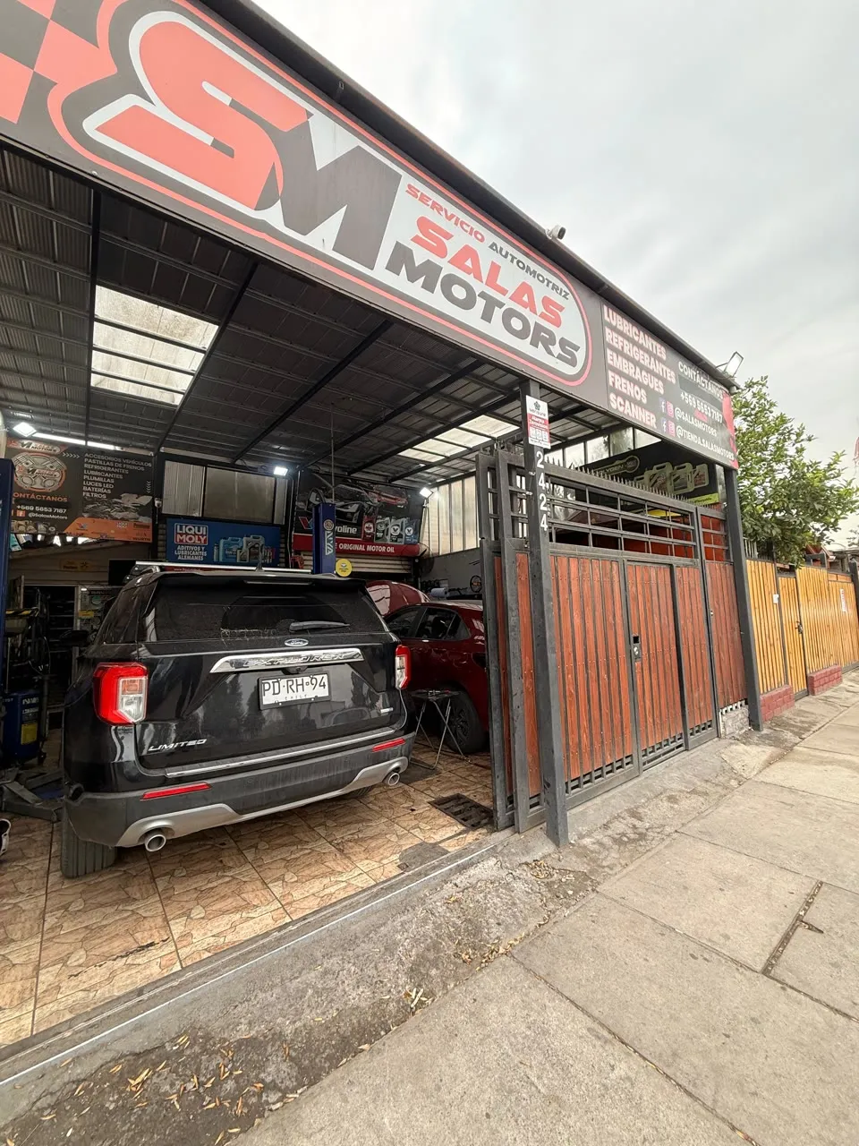 Entrada de SalasMotors con el letrero del taller sobre el portón y una camioneta negra adentro