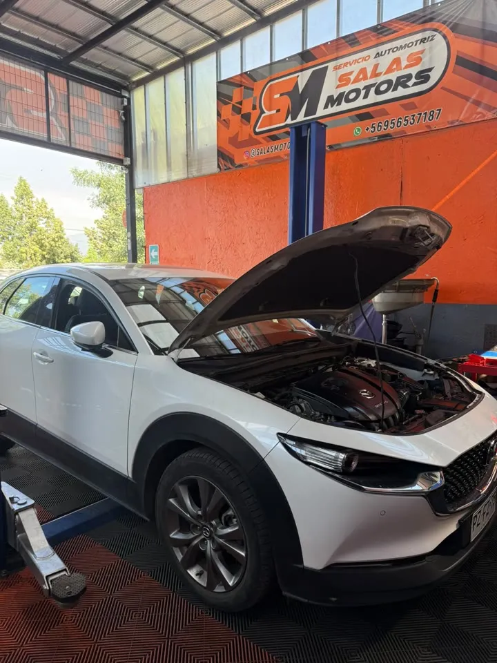 Mazda CX-30 blanco con el capó abierto en un elevador
