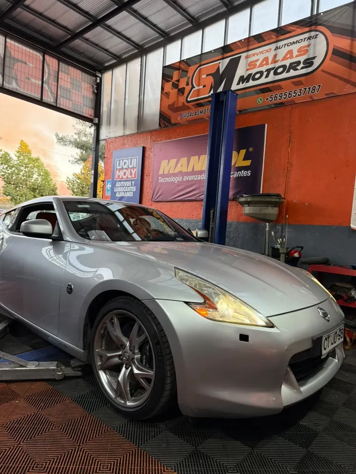 Nissan 370Z plateado en el taller, frente a un letrero de Mannol