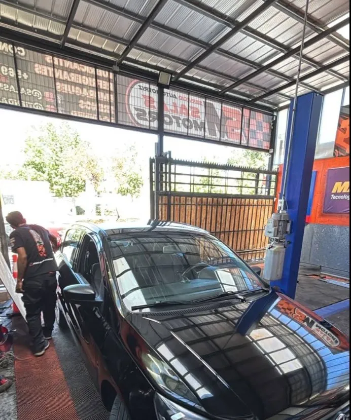 Auto negro entrando al taller SalasMotors, bajo el letrero del taller