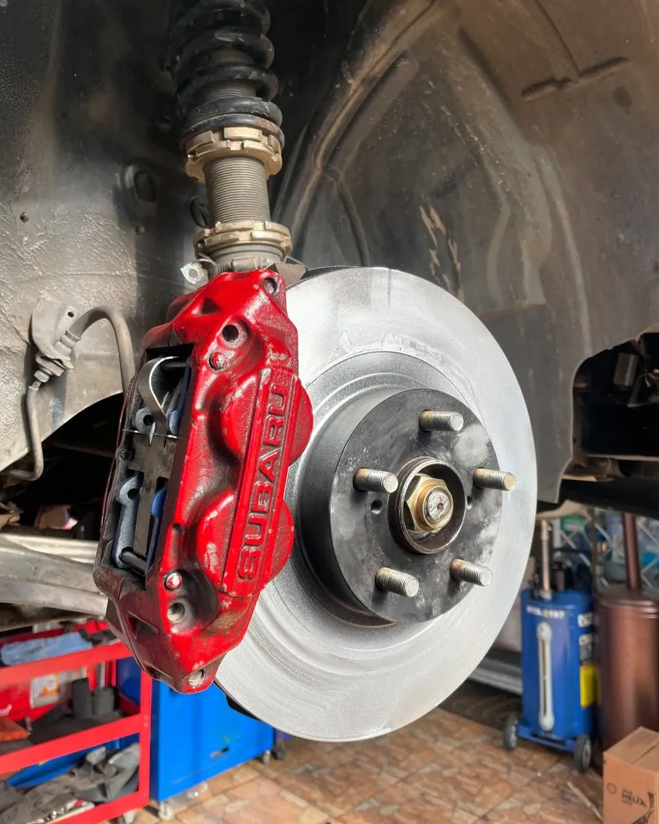 Caliper de freno rojo y disco del Subaru, con la rueda desmontada